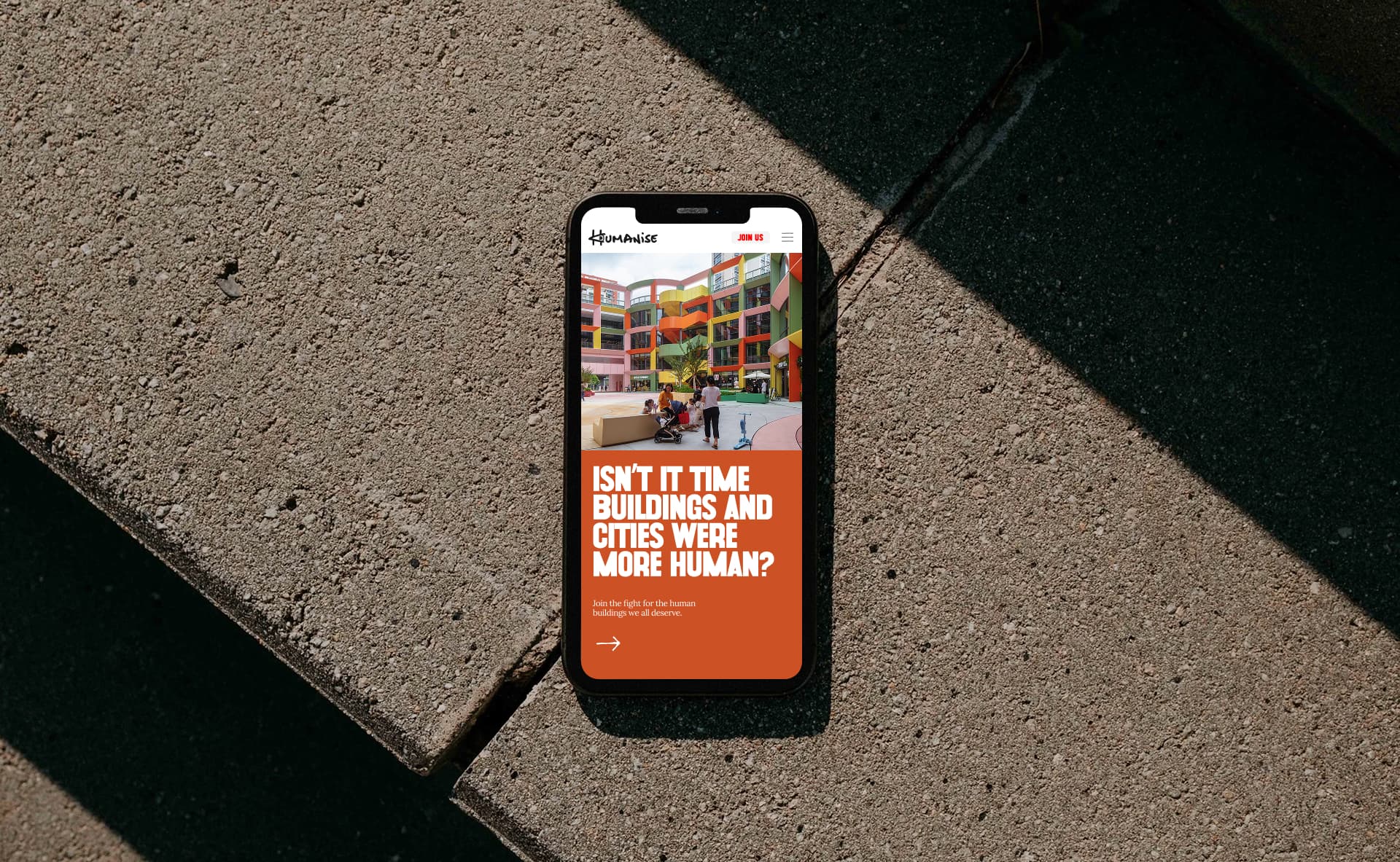Mobile phone on concrete with Humanise website on screen